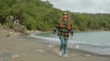 Deniz kenarındaki eski evlerin kalıntıları kıyıları keşfeden genç bir kadının arkasında. Eski şehirleri gezmek.