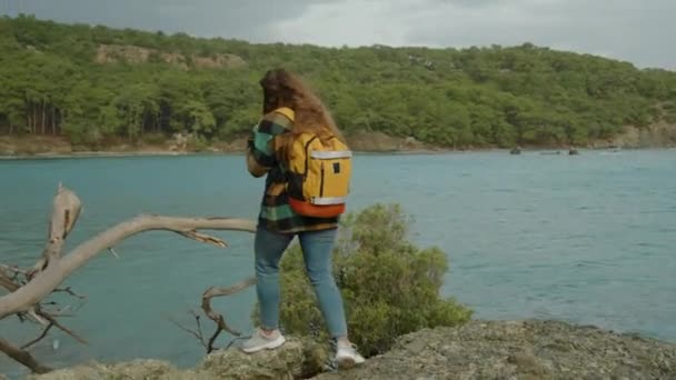 Seorang Wisatawan Perempuan Muda Dengan Ransel Turun Dari Tebing Laut — Stok Video