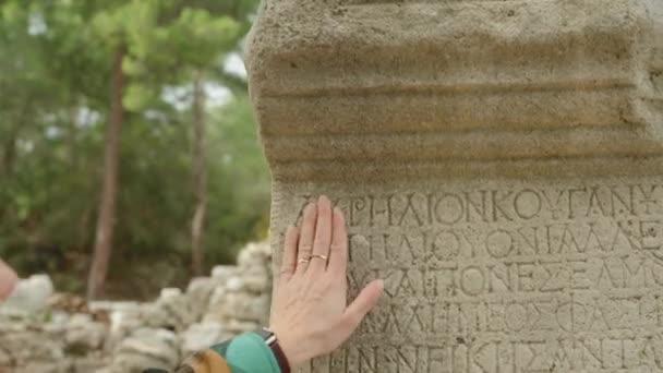 Μια Νεαρή Τουρίστρια Αγγίζει Αρχαίους Λίθινους Κίονες Ελληνικές Επιγραφές Σκαλισμένες — Αρχείο Βίντεο