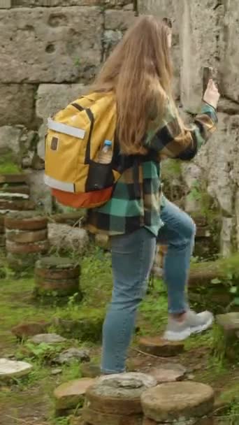垂直录像 一位年轻的女旅行家带着背包游览了一座古希腊城市的废墟 并为社交媒体或纪念品拍照 — 图库视频影像