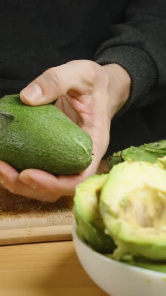 Ein Mann Schneidet Eine Avocado Zwei Hälften Und Entfernt Mit — Stockvideo