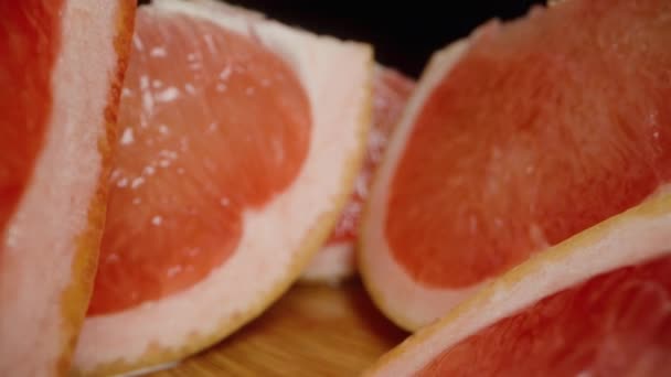 Gesneden Grapefruit Partjes Met Rood Sappig Vlees Een Zwarte Achtergrond — Stockvideo