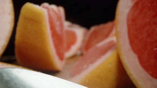 Kesilmiş Greyfurt Dilimleri Tahtaya Siyah Bir Zemin Üzerine Şeker Serpiştirilmiş — Stok video