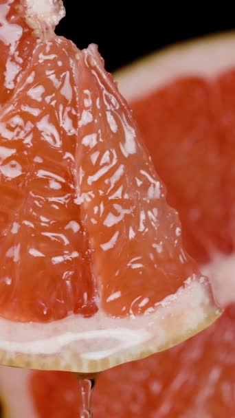 バーティカルビデオ ゆっくりとした動きでは ジュースはグレープフルーツのくさびからドロップされます 赤いジューシーな肉のクローズアップ — ストック動画