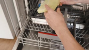 Kadın bulaşık makinesini sallıyor ve onu yavaş çekimde kürsüye koyuyor..