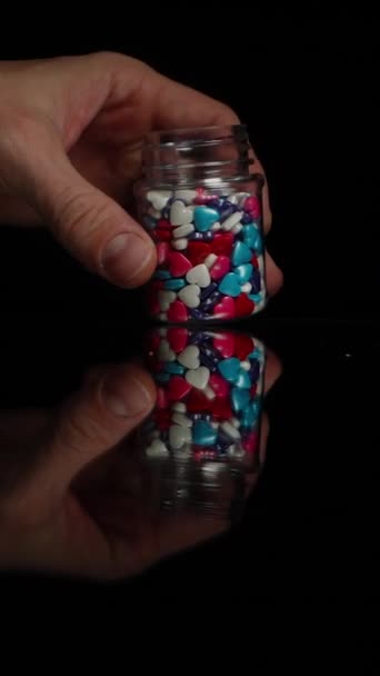 Vídeo Vertical Corazones Azúcar Multicolores Derramándose Desde Tarro Sobre Una — Vídeo de stock