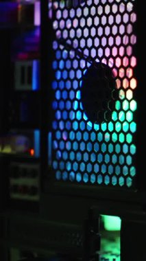Dikey video. Teknolojik sıçrama ekranı için arka plan, gökkuşağı ışıklandırmalı bir oyun bilgisayarının elektronik parçaları. Çerçeve boyunca yavaş odaklanma tekniği.