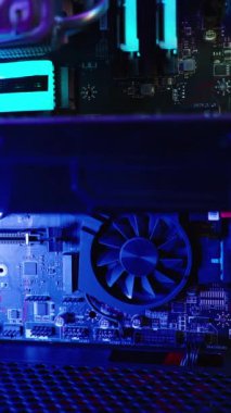 Dikey video. Gökkuşağı RGB ışıklandırmalı, ışıltılı, birbirine bağlı bir grafik kartı olan ana kart. Bilgisayarın içine bak.