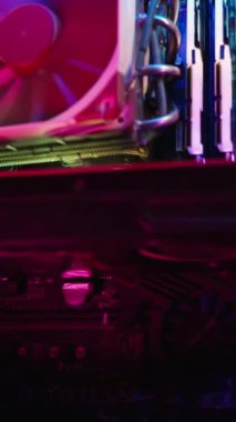 Dikey video. Karanlıkta, bir oyun masası bilgisayarı gökkuşağı ışığıyla parıldıyor, iç bileşenlere yakın çekim.