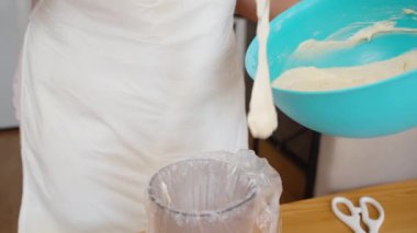 Bir kadın kekler için hazırlanırken sıvı hamuru torbaya koyar..