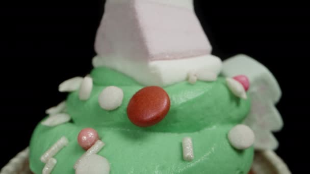 緑色のフロスティングと火の木型のマシュマロ 新年の装飾を施したカップケーキ 黒い背景で孤立した ドリースライダー クローズアップ — ストック動画