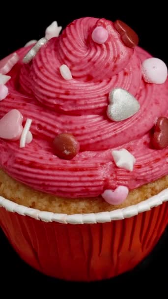 粉红色结霜杯蛋糕 饰有红心 环状旋转在黑色背景上 — 图库视频影像