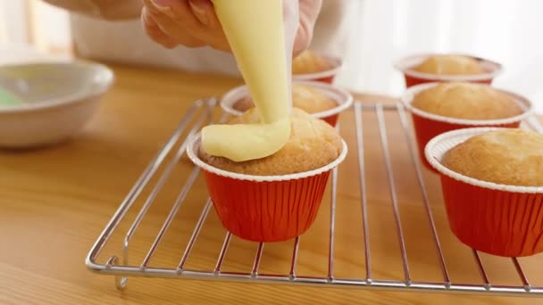 黄色的奶油从糕点袋中挤压成圆形 装在红色衬里的纸杯蛋糕上 — 图库视频影像