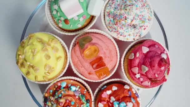 お祝いカップケーキが皿の上に回っています マーマレードで作られた フロスティングの上にハート型のスパイク — ストック動画