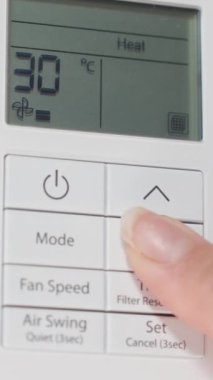 Dikey video. Beyaz bir duvardaki klima için uzaktan kumanda, sıcak hissetmek, kadın sıcaklığı düşürür ve sonunda kapatır..