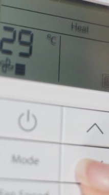 Dikey video. Duvardaki beyaz klimanın uzaktan kumandasını kapat, kadın sıcaklığı düşürür ve kapatır..