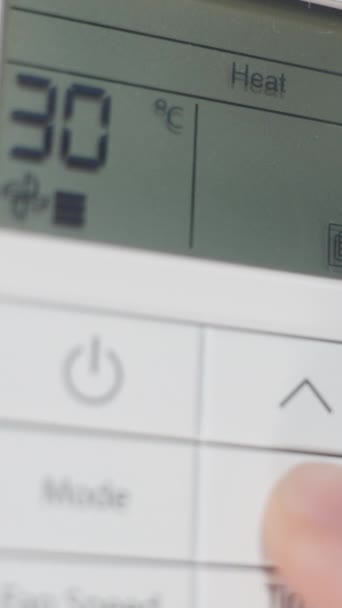 バーティカルビデオ 暖房モードの壁に取り付けられたエアコンのリモート コントロールの閉鎖 熱く感じる 男は温度を下げる — ストック動画