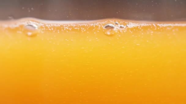 オレンジジュースまたはソーダマクロショット ガラスの泡と液体レベル スローモーション — ストック動画