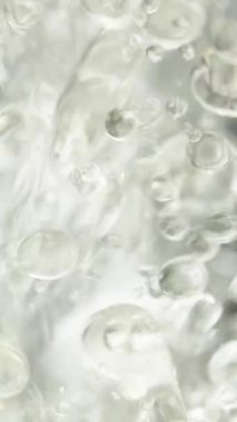 Dikey video. Sudaki binlerce yağ damlası, siyah arka planda hava kabarcıkları. Makro çekim.