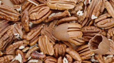 Hem soyulmuş hem de kabuksuz cevizlerle kaplı bir masanın üst görüntüsü.