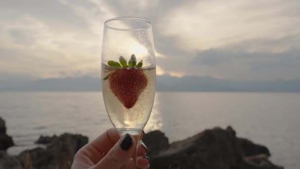 Aardbei Glas Champagne Vrouwenhanden Maakt Bubbels Tegen Zonsondergang Door Zee — Stockvideo
