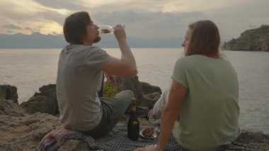 Deniz Tarafından Günbatımında Genç Bir Çift, Erkek Şampanya İçiyor ve Kadınlara Çilek Veriyor.