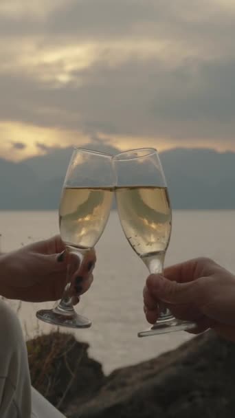 バーティカルビデオ 男と女は海の夕日に対するシャンパングラスをクランク ロマンチックな日付 — ストック動画