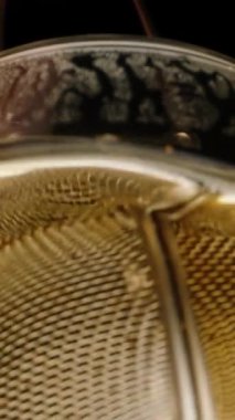 Dikey video. Çay yapraklarıyla dolu metal ağ çözücü kullanarak çay demlemek. Makro düşük açılı bir atış..