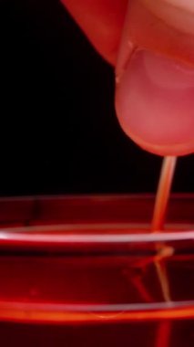 Dikey video. Çay demliğini bardaktan kaldırırken, kuru yapraklar içerideydi, kırmızı çay, damlalar düşüyordu. Makro. Yavaş çekim.