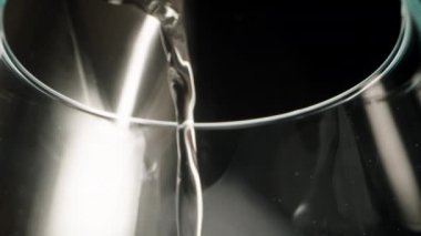 Kaynayan su, bardağa metal bir su ısıtıcısından dökülüyor, bardağın içindeki süper makro görüntü. Buhar yavaşça yukarı doğru yükseliyor..