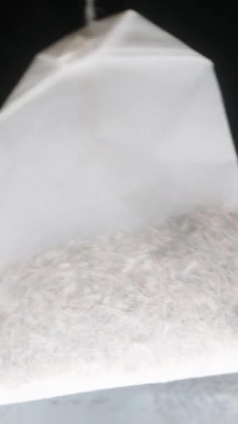 バーティカルビデオ 使い捨て可能なティーバッグは 沸騰した水でガラスに浸され ガラスの底からマクロビュー — ストック動画