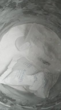 Dikey video. İçinde beyaz toz olan siyah bir kavanozun üstünde tepeden tırnağa görüntü ve etrafındaki her yerde toz. Yavaş çekim.