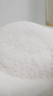 Dikey video. Bir kaşıkla şeker toplar ve bir bardağa doldururum. POV, Yavaş Hareket.
