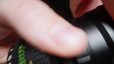 Bir adam lens kapağını çıkarır ve içinde ne olduğunu gösterir. Yakın plan..