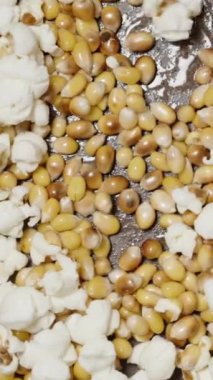 Dikey video. Mısır taneleri çerçeveden yukarı doğru çıkar ve uçar. Dönüp tavanın üstüne düşüyorlar..