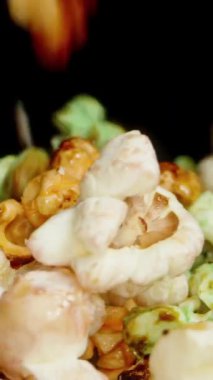 Dikey video. Yukarıdan düşen tatlı renkli patlamış mısırlardan oluşan bir dağ. Ağır çekim. Kaydırıcı.