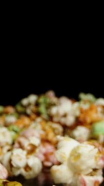 Dikey video. Erkek eller masadan birer birer avuç patlamış mısır alır. Yavaş çekim makro doli.