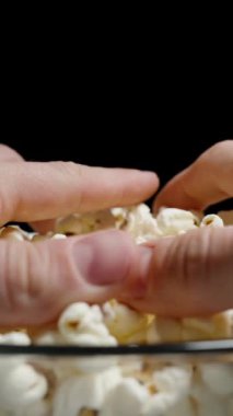 Dikey video. Her iki taraftan da bir avuç patlamış mısırı tabaktan alın. Yavaş çekim.