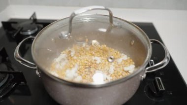 Patlamış mısır çekirdekleri tencerede kızartılıyor ve yavaş çekimde patlamaya başlıyor..