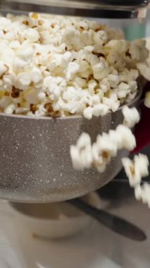 Dikey video. Patlamış mısırla dolu bir tencere büyük bir kaseye doldurulur..