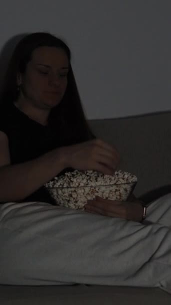 Vídeo Vertical Uma Mulher Senta Sofá Comendo Pipocas Com Luz — Vídeo de Stock