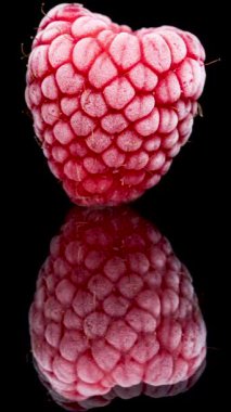 Dikey video. Buzla kaplı donmuş ahududu, siyah aynalı arka planda hızla erir..