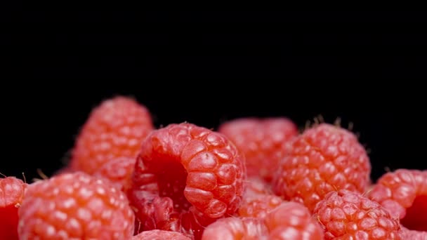 A handful of raspberries rotating on a black background, close-up.