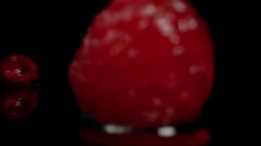 Ahududu böğürtlenleri masaya su sıçratarak düşerken geri çekiliyorlar. Yavaş çekim.