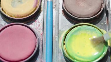 Farklı renklerde suluboya boya, sarı boya toplayan bir fırça. Kaydırıcı, yakın plan.