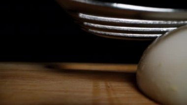 Haşlanmış tavuk yumurtaları ezilir ve ahşap bir masada çatalla ezilir. Dolly kaydırıcı, yakın plan..