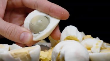 Adam haşlanmış yumurtanın sarısını çıkartıyor. Yakın plan. Masada çok yumurta var..