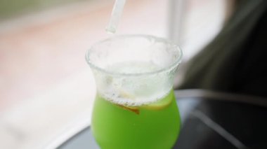 Yeşil bir Alkolik Kokteyli Kamışla Karıştırıyorum ve Bardağın Halkasına Serpiştiriyorum.