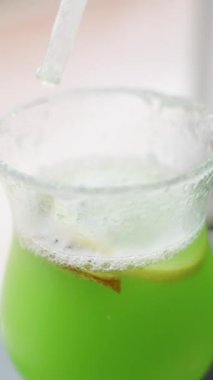 Vertical video. I Stir a Green Alcoholic Cocktail With a Straw and Sprinkle Salt on the Rim of the Glass.