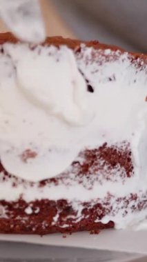 Dikey video. Kırmızı katmanlı ve beyaz kremalı katmanlı pasta kenarlara yayılmış..